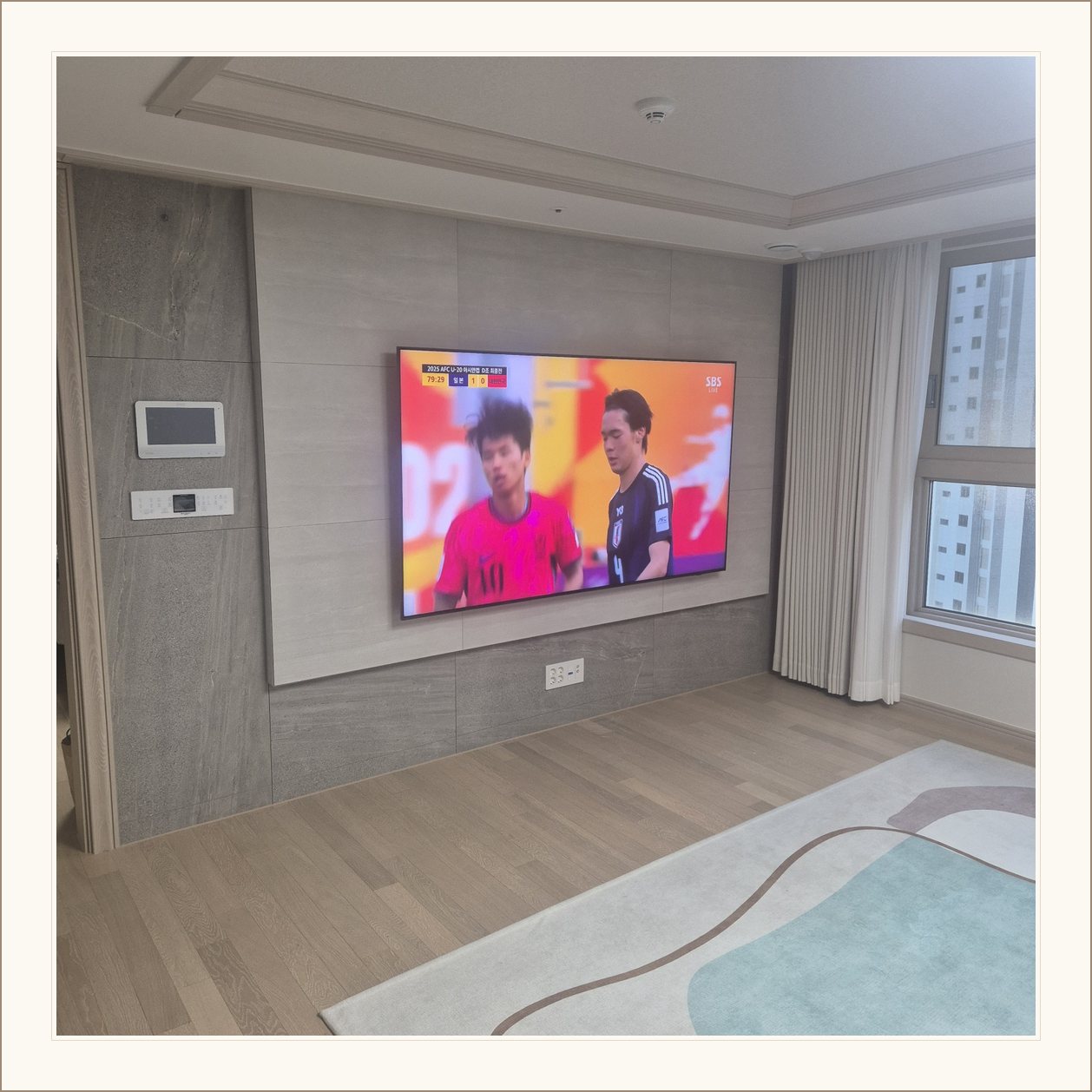 밝은 회색 아트월과 시청 공간, 밝은 몰딩과 TV 아래 전원 위치가 같이 나타납니다
