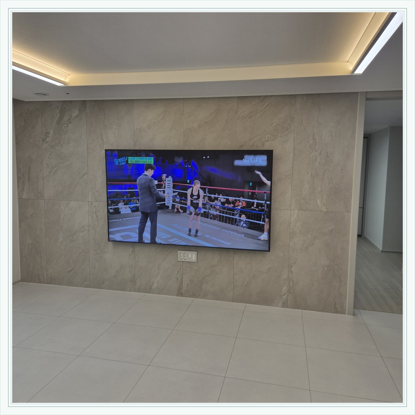 돌무늬 패널과 대형 TV, 벽 무늬가 화면 양쪽으로 이어져 중심 배치가 눈에 띕니다