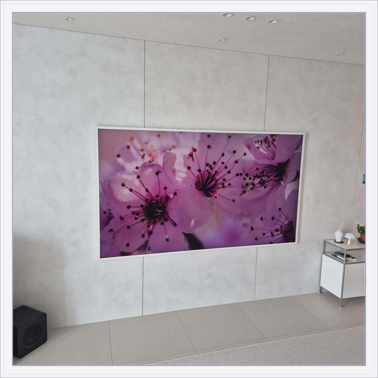 꽃 화면이 나오는 흰색 프레임 TV, 밝은 패널 위 흰 테두리와 꽃 영상의 색 대비가 큽니다