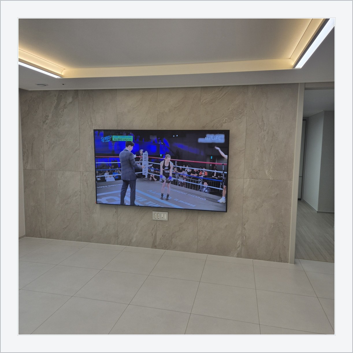 돌무늬 패널과 대형 TV, TV 아래 콘센트 패널이 드러나는 구도입니다